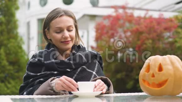 快乐的女人喝茶向南瓜杰克微笑万圣节庆典视频的预览图