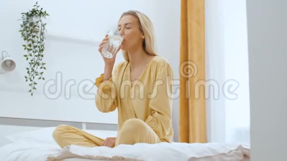 年轻女子坐在床上喝水视频的预览图