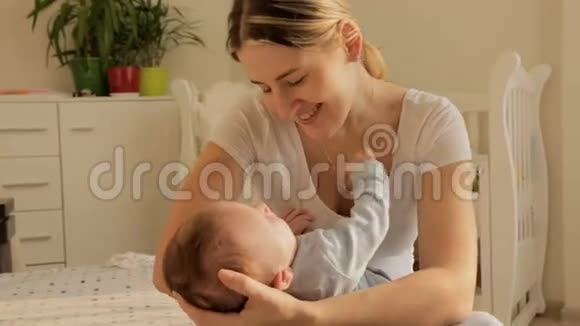 快乐的年轻妈妈在卧室里摇着她三个月大的小男孩视频的预览图