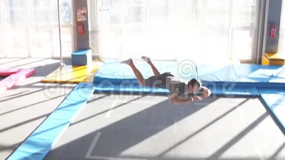 年轻健康快乐的人在健身馆的蹦床上跳跃视频的预览图