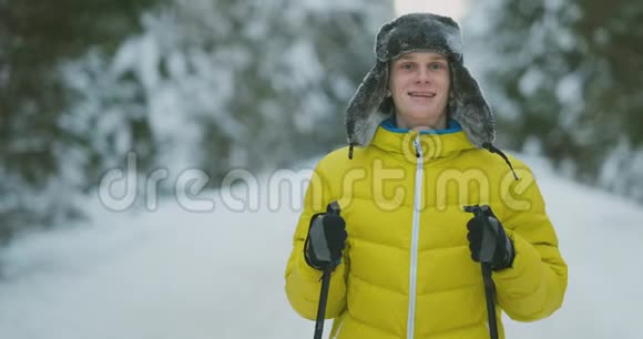 在冬天的森林旅行中带着滑雪板的微笑男人和他的妻子在看一些奇怪的东西视频的预览图