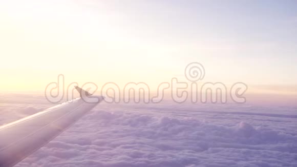 从窗口看日落时金色天空中飞翔的飞机和白云的翅膀窗外美景视频的预览图