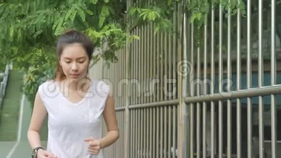 年轻的亚洲运动女性在城市公园日出前热身和伸展运动视频的预览图