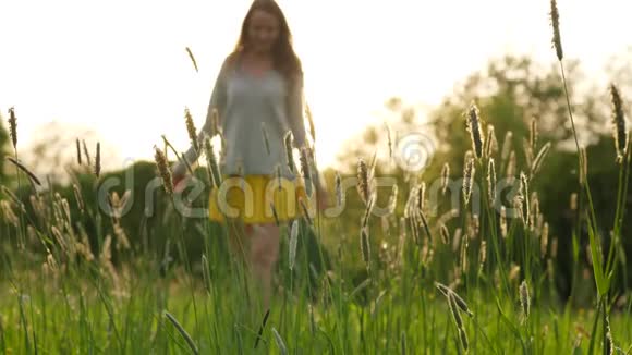 女人走在绿草如茵的田野上视频的预览图