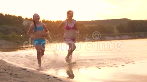 女孩们在沙滩上奔跑在海滩上溅起水滴笑着快乐自由的青少年视频的预览图