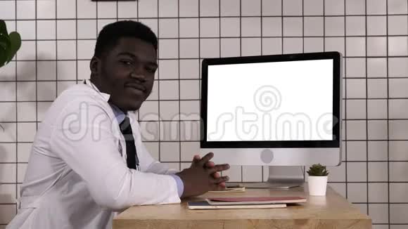 坐在电脑屏幕旁边的黑人医生和摄像机说话白色显示器视频的预览图