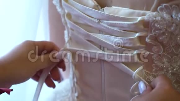 婚纱特写伴娘用蝴蝶结向婚纱鞠躬新娘正在准备婚礼球球视频的预览图