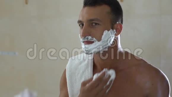 男人在脸上涂剃须膏早上在浴室里拿着安全剃刀视频的预览图