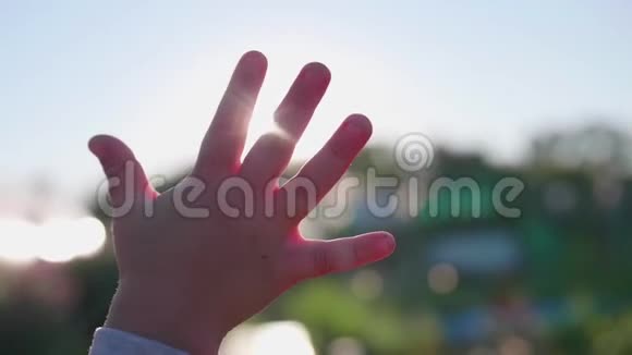 一个小朋友笔向太阳招手光线穿过你的手指欢迎来到太阳视频的预览图