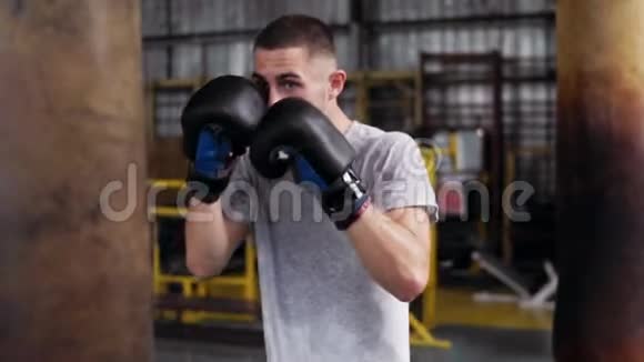 一个年轻的短头发的男拳击手用黑色拳击手套做结实的布丁用冲压袋工作视频的预览图