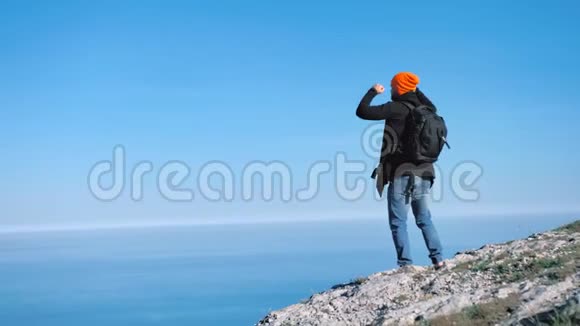 成功的徒步旅行者获胜者男子庆祝胜利站在蓝天悬崖的顶峰视频的预览图