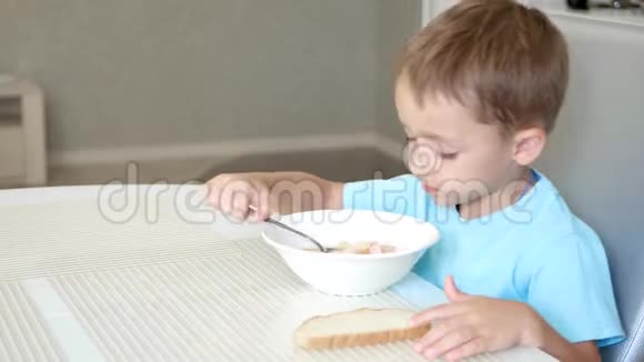 孩子坐在厨房的餐桌前吃香肠汤健康宝宝食品的概念视频的预览图