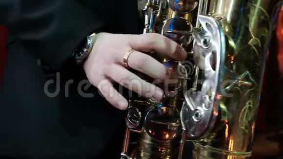 在旧萨克斯管上演奏的人的低音特写爵士球员排练视频的预览图