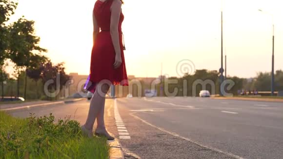 穿红裙子的女人在路上搭便车做长臂开车视频的预览图