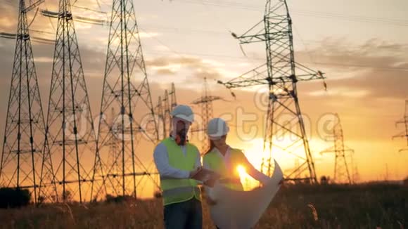 两名工程师在电力线附近统一工作日落背景视频的预览图