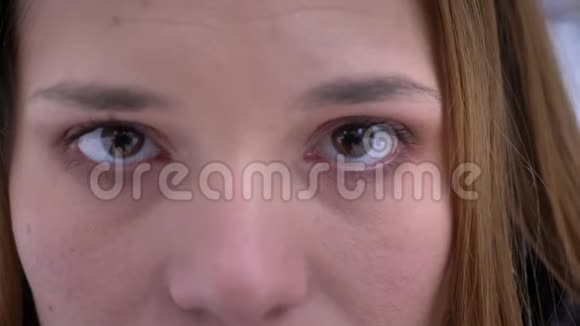 年轻漂亮的白种人女性面部特写镜头棕色眼睛注视着沉思中的镜头视频的预览图