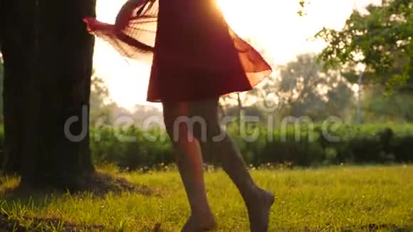 快乐的女孩在绿色的田野上跳舞美丽的红色连衣裙轻盈的连衣裙在空中飞翔视频的预览图