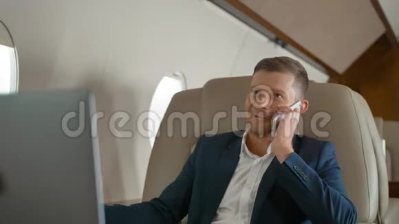 富有的成熟商人在商务飞机上旅行时通过电话交谈视频的预览图