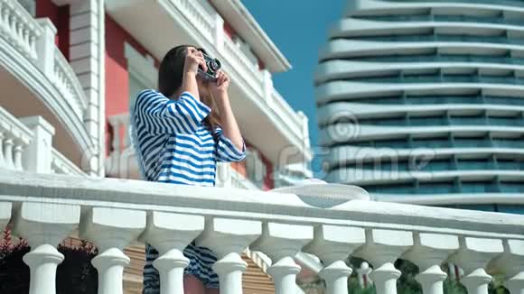 女专业摄影师太阳镜和条纹连衣裙使用老式相机拍照视频的预览图