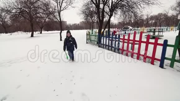 一个快乐的男孩在雪地上和孩子们一起跑挥手视频的预览图