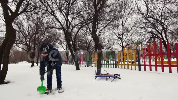 高清开朗的男孩正在雪地里和孩子们玩铲子视频的预览图