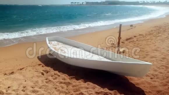 在风和日丽的天气躺在沙滩上钓鱼的白色木船的4k镜头视频的预览图