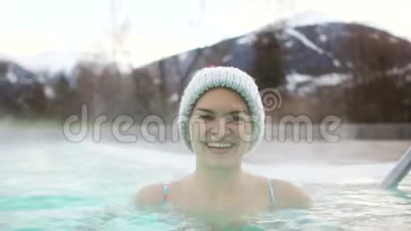 美丽的黑发在冬天的温泉里洗澡一个女孩戴着一顶针织帽子视频的预览图