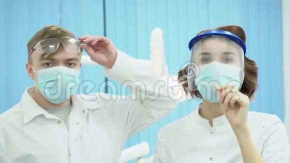 戴口罩和护目镜的男女牙医媒体戴防护无菌制服的牙科医生视频的预览图