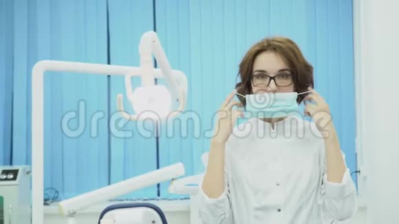 女牙医在牙科办公室戴面具媒体戴口罩和白大褂的漂亮女牙医准备工作视频的预览图