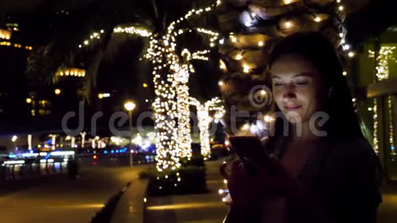 有魅力的女人晚上用智能手机视频的预览图