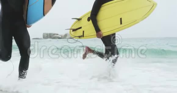 两名男性冲浪者用冲浪板在海滩上跑4k视频的预览图