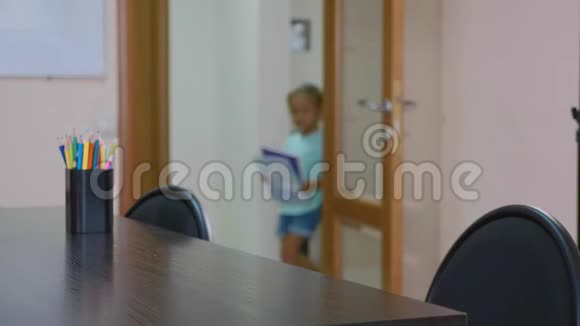 小可爱的女孩走进教室坐在桌子旁开始学习视频的预览图