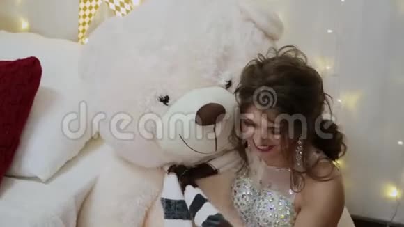 非常漂亮的女孩抱着一只大熊在圣诞床上视频的预览图