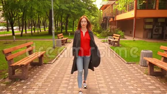 红头发的女性散步环绕着绿树和青草视频的预览图