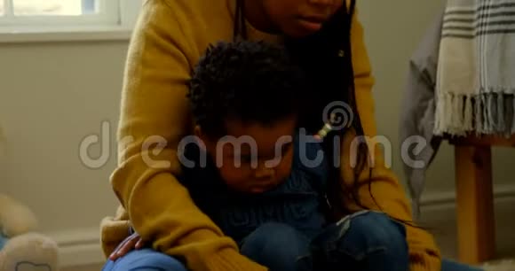 年轻的黑人母亲在舒适的家中与儿子玩耍的正面景色视频的预览图