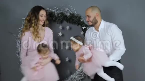 家庭关系快乐的年轻父母在灰墙的背景下和女儿玩耍圣诞节大片视频的预览图