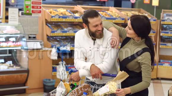 一对年轻夫妇在超市里挑选新鲜面包的肖像视频的预览图
