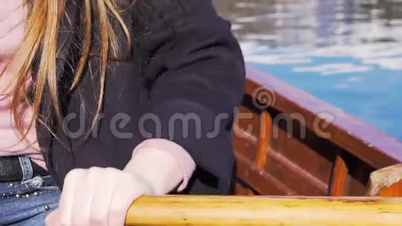 慢动作特写阳光明媚的一天年轻女子的手在木船上划桨视频的预览图