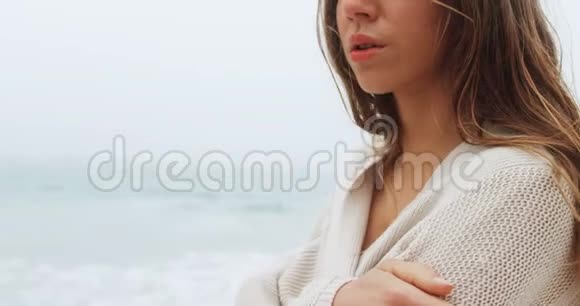 白种人妇女用手臂在海滩上交叉行走的侧面景色视频的预览图