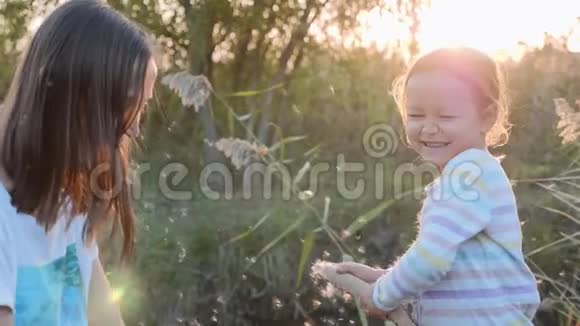 妈妈和女儿玩得开心一边吹蒲公英种子一边在大自然中放松视频的预览图