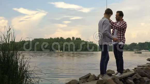 父亲和16岁的儿子准备钓鱼竿在湖边一起放松视频的预览图