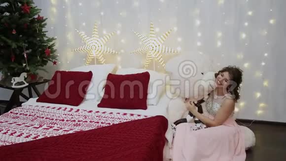 非常漂亮的女孩抱着一只大熊在圣诞床上视频的预览图