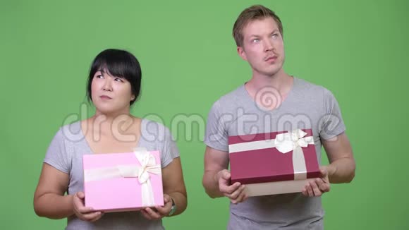 年轻幸福的多民族夫妻手捧礼盒一起思考视频的预览图