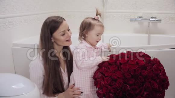 母亲和小女儿闻花的侧景视频的预览图