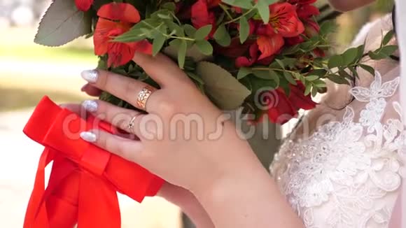 身着白色婚纱的年轻新娘手中捧着美丽的红色新娘花束慢动作一个年轻女孩视频的预览图