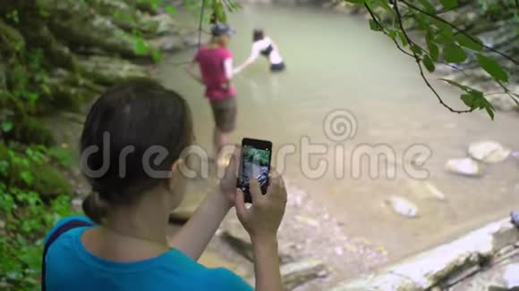 一位女士用智能手机拍摄两个女孩的照片视频的预览图