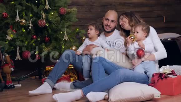 家庭圣诞父母和孩子和小狗坐在一起看背景圣诞树上的摄像机视频的预览图