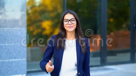 赢家成功商务小姐Brunette穿在办公楼背景上对着镜头微笑竖起大拇指视频的预览图