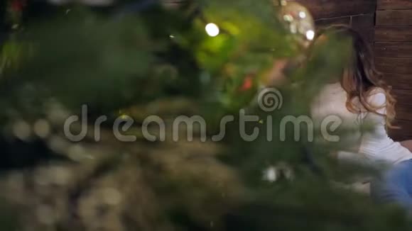 圣诞前夜一家人坐在被照亮的圣诞树下男人和女人互相摸鼻子视频的预览图