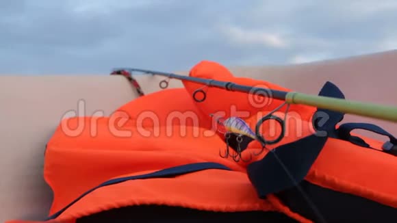 前景中的橙色救生衣和钓鱼竿视频的预览图